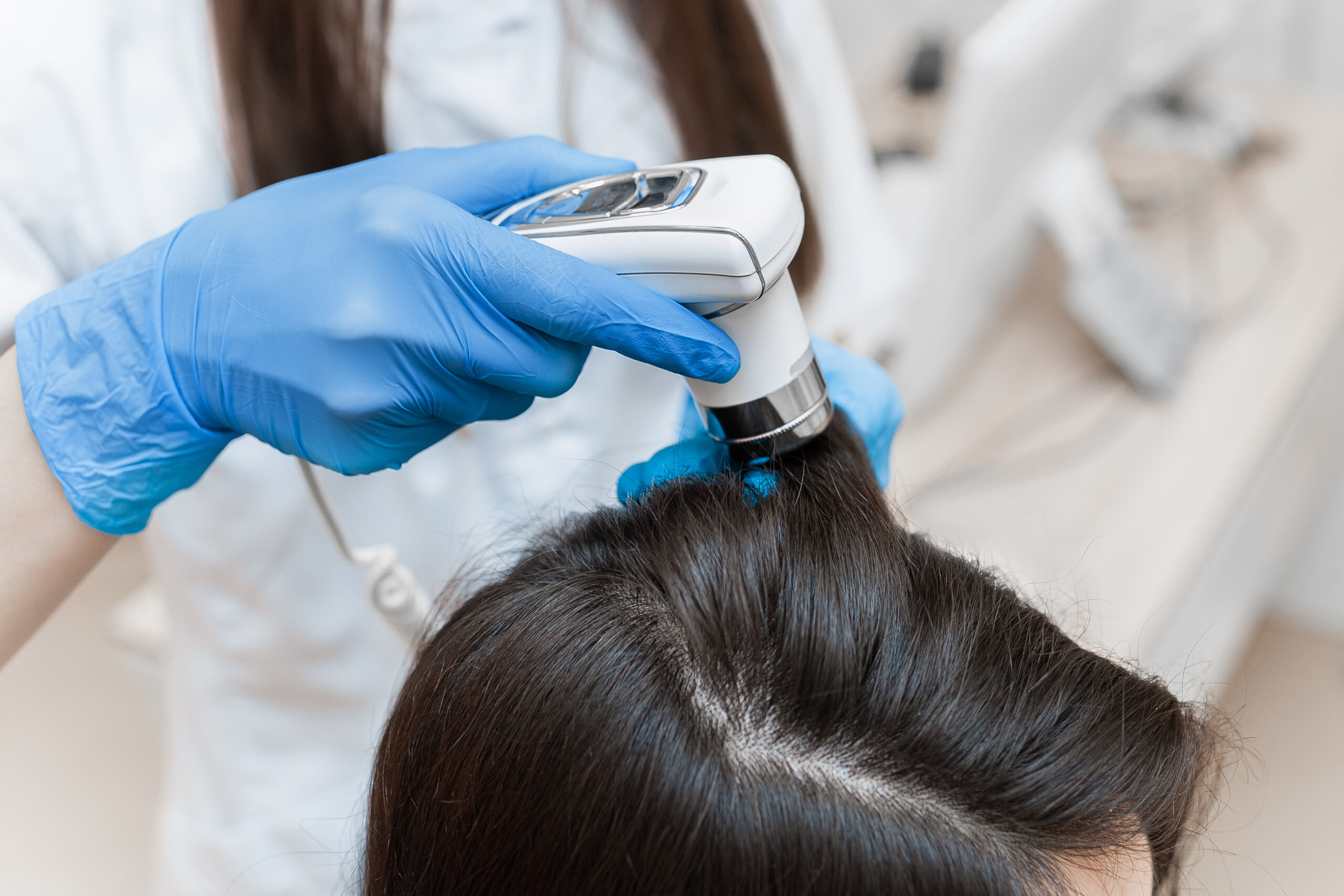 A stylist uses a diagnostic tool on a client's scalp, assessing hair health in a professional salon setting.